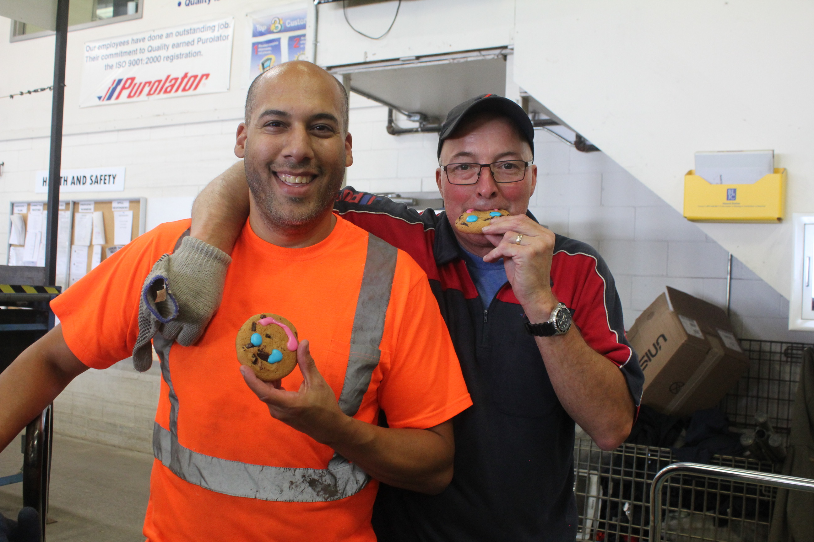 Two Purolator staff eating cookies